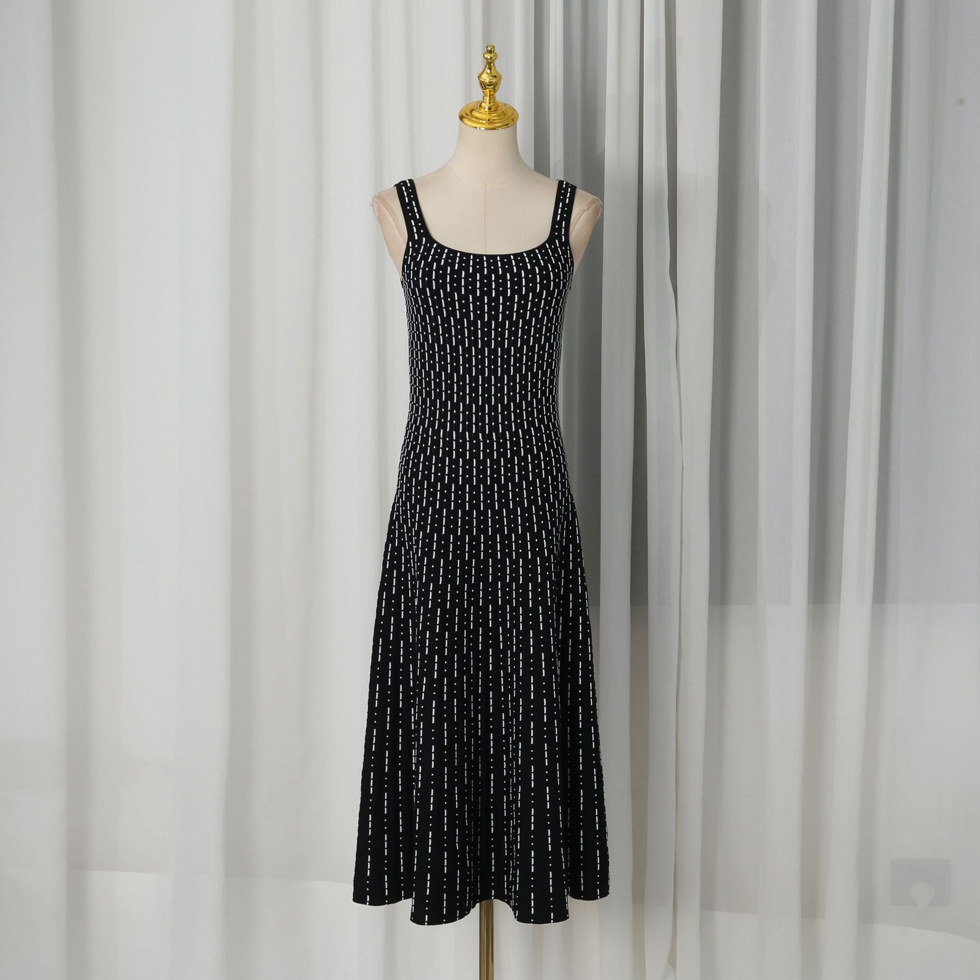 Black sleeveless maxi dress on mannequin with scattered white dot pattern, scoop neck