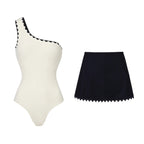White one-piece swimsuit and dark swim skirt with black scalloped trim
