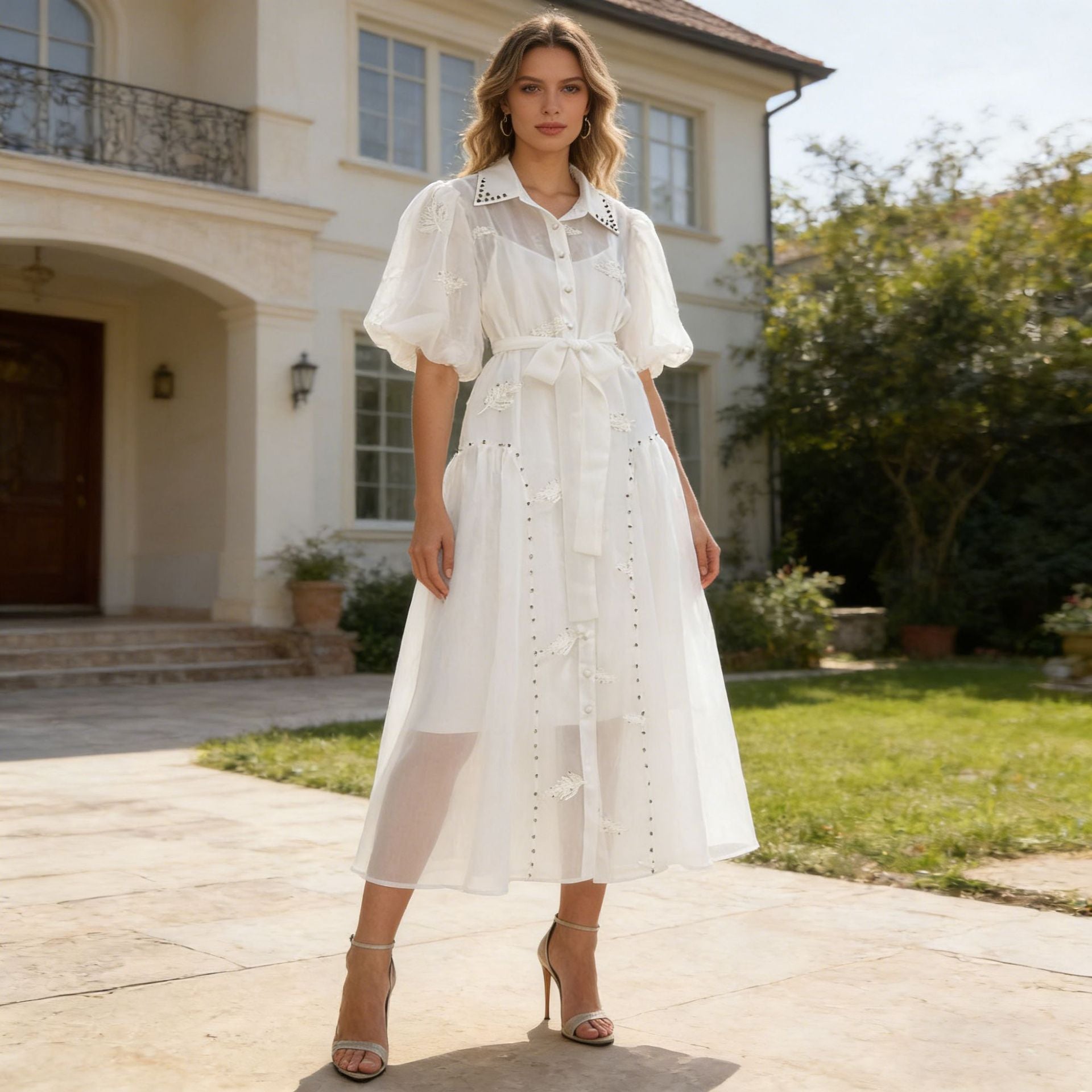 White maxi dress with puff sleeves, button front, lace trim, and tied waist belt