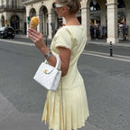 Back view of women's pale yellow lace-trim pleated dress with low back and short sleeves