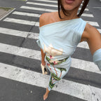 Light blue one-shoulder sheath dress with green and red floral print, close-up