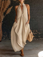 Beige sleeveless halter maxi dress with deep V neckline and flowing skirt