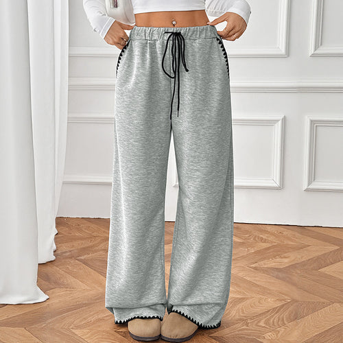 Gray wide-leg sweatpants with high waist, black drawstring, and contrast trim at hems
