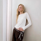 White long-sleeve top with faux camisole overlay and side tie hem detail