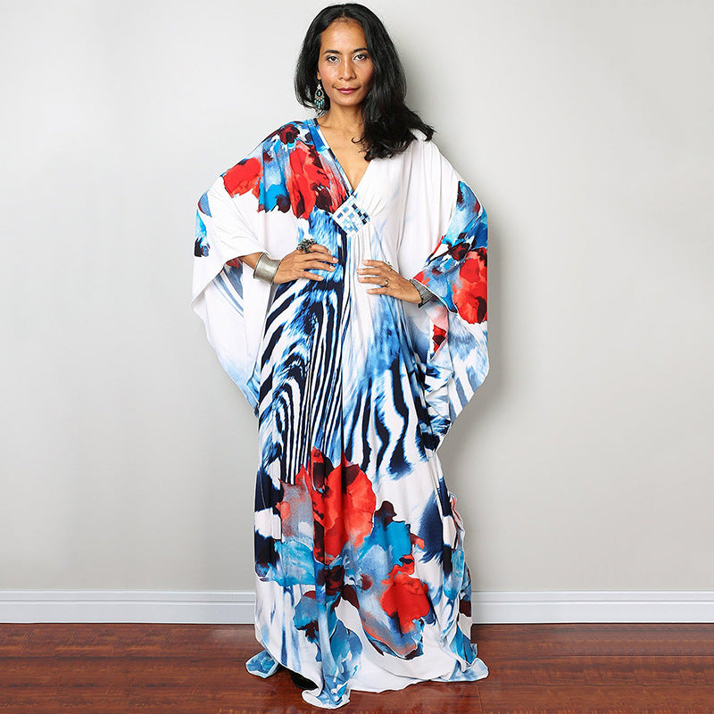 One-piece beach dress with white base and blue, black, and red floral splash print
