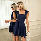 Navy blue short dress with ruffled cap sleeves, bow waist, tiered skirt, open back.