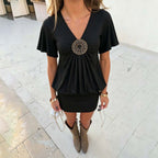 Women's black pleated short-sleeve dress, deep V-neck, with circular medallion bust detail