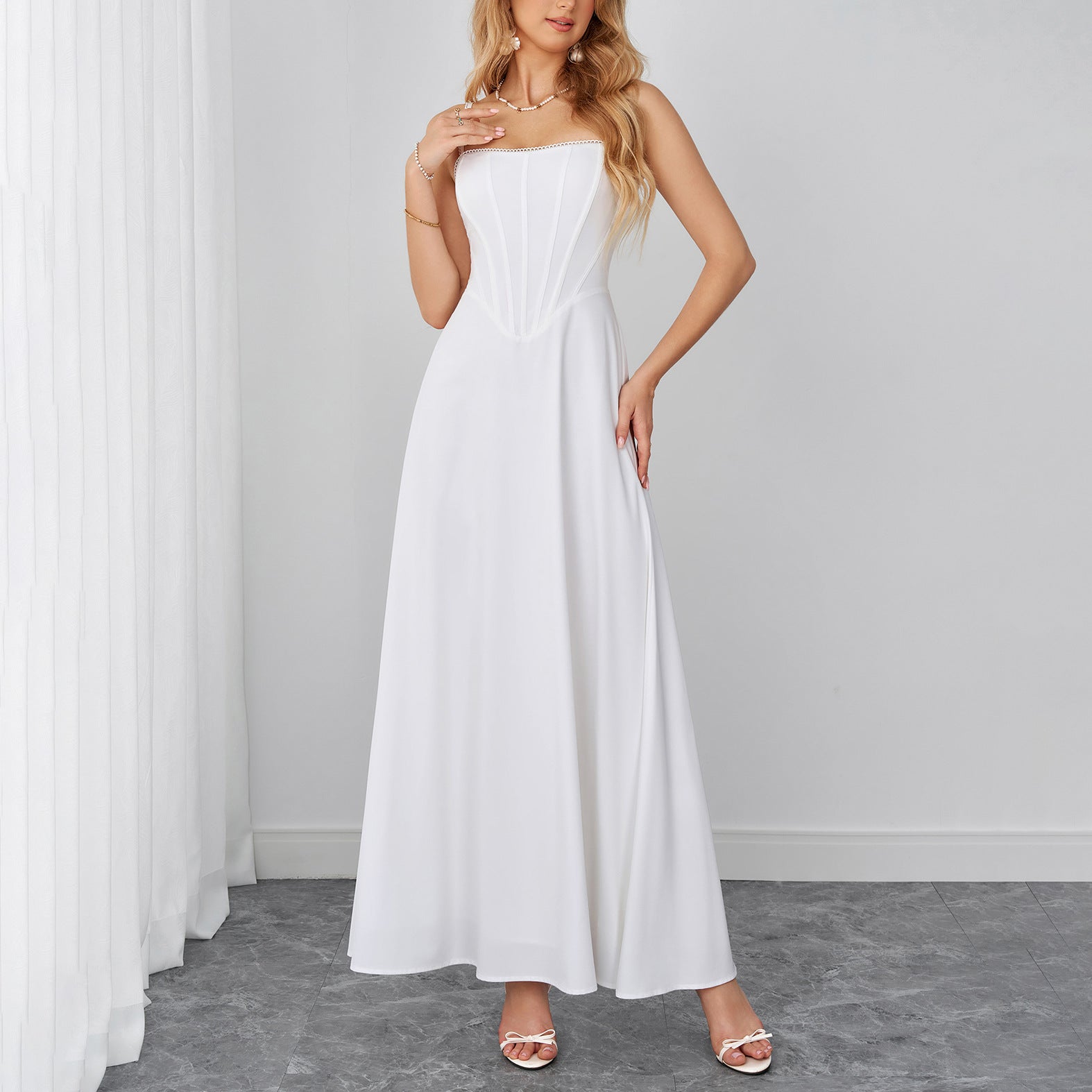 White sleeveless maxi dress with sweetheart neckline and flowing A-line skirt.