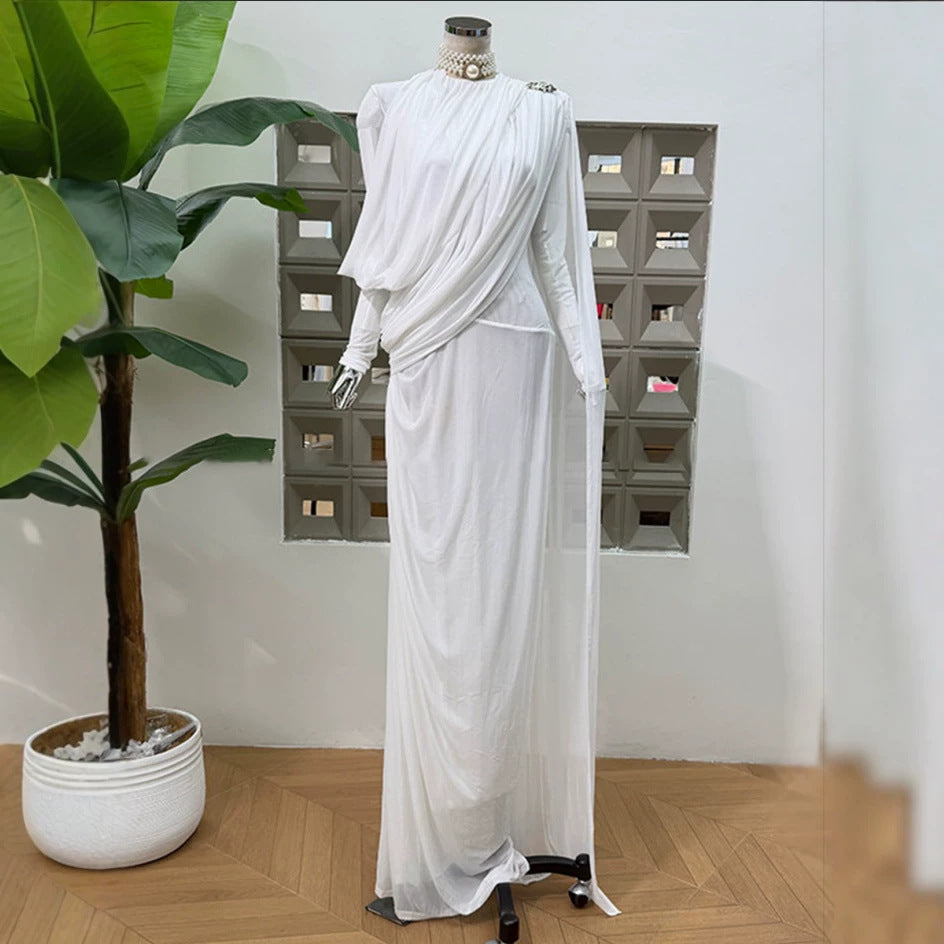 White pleated formal dress with long sleeves, diagonal drape detail, flowing maxi skirt