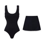 Black one-piece swimsuit and matching skirt with white scalloped trim