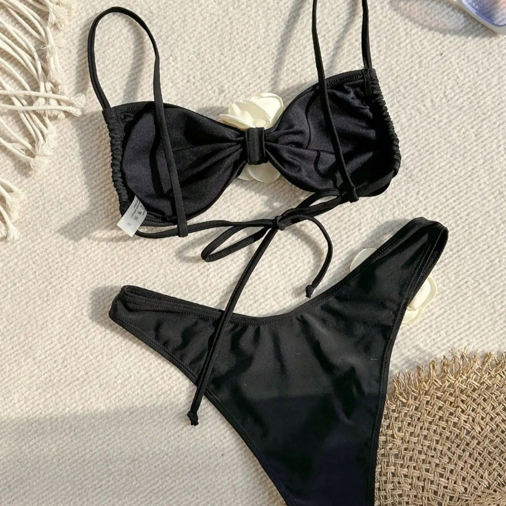 Black bikini set with bow-tie front and high-cut bottoms, white flower detail