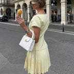 Women's pale yellow lace-trim pleated dress, low back and short sleeves, side view