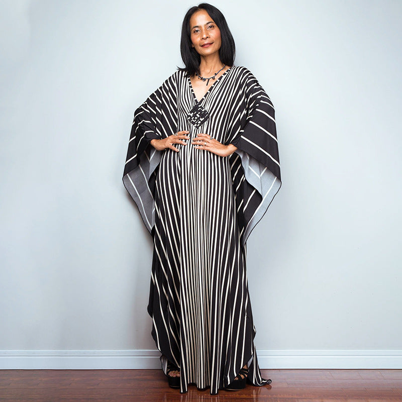 One-piece beach dress in black with white vertical stripes and draped kaftan sleeves