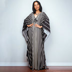 One-piece beach dress in black with white vertical stripes and draped kaftan sleeves