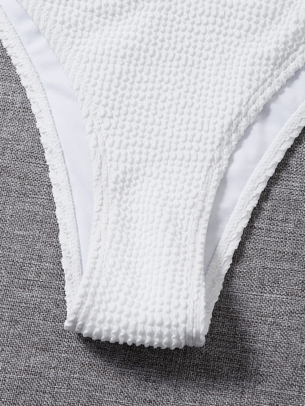 Close-up of white textured low-rise bikini bottoms with narrow side coverage