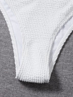 Close-up of white textured low-rise bikini bottoms with narrow side coverage