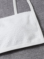 Close-up of white textured bandeau bikini top with thin shoulder straps