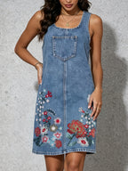 Blue denim sleeveless sling dress with chest pocket and floral embroidery on lower skirt