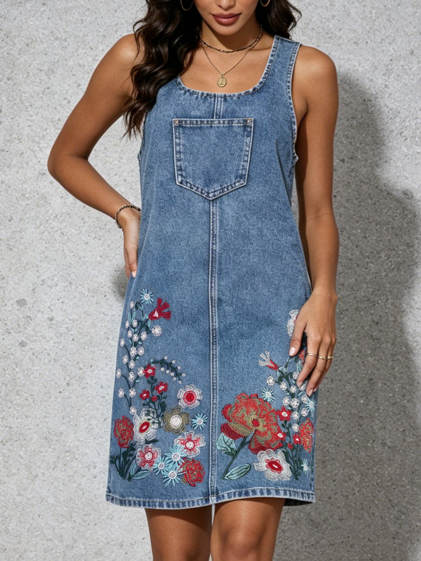 Blue denim sleeveless sling dress with chest pocket and floral embroidery on lower skirt