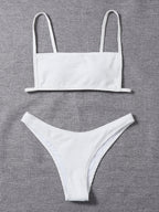 White textured bikini set laid flat: bandeau top with thin straps and low-rise briefs
