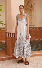 Women's sleeveless white embroidered dress with blue motif border, gathered waist and bows