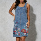 Blue denim sleeveless sling dress with front chest pocket and embroidered floral panel