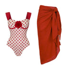 Red polka-dot one-piece swimsuit with rose plus matching red wrap skirt, knotted waist