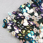 Close-up of multicolor sequins on dark fabric with pink feather trim edge