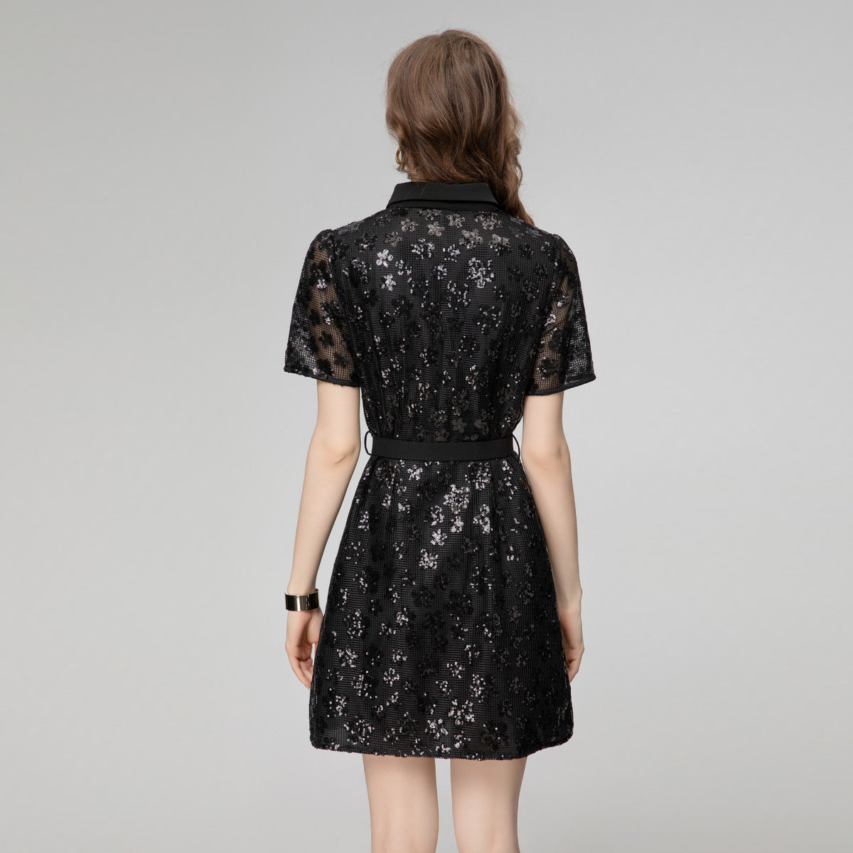 Black sequin short sleeve dress from back view with waist belt and button detail